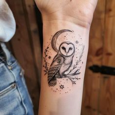 an owl tattoo on the wrist with stars and a half moon in the background,