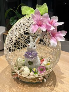 a basket filled with flowers and an easter bunny figurine sitting on top of a table