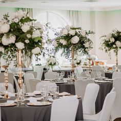 the tables are set with white flowers and silver linens for an elegant wedding reception