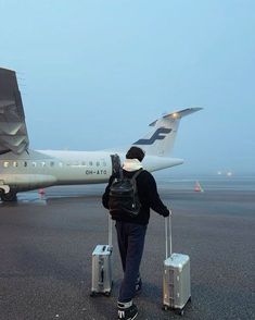 a man with two suitcases standing in front of an airplane