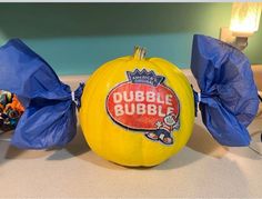 a yellow pumpkin sitting on top of a table covered in blue plastic wrappers and some candy