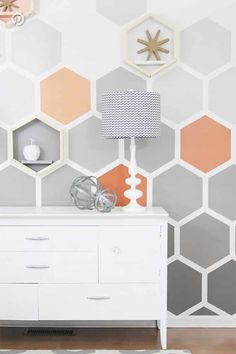 a white dresser sitting in front of a wall with hexagonal tiles on it