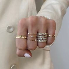 a woman's hand with three different rings on it and one is wearing a white coat