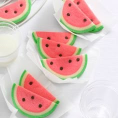 four slices of watermelon sitting on top of napkins next to a bottle of milk