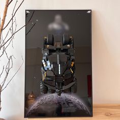 a framed photo of a lego batman batmobile on a table next to a tree