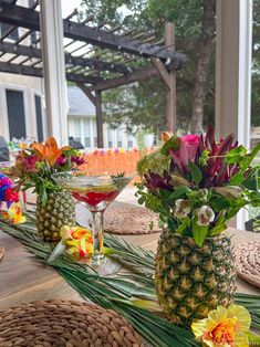 pineapples and tropical flowers are arranged on the table for an outdoor cocktail party