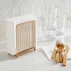 gold utensils and napkin holders on a white counter