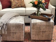 a living room with a couch, ottoman and flowers in a vase on the coffee table