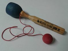 an old wooden mallet and two red balls on a white table with string in the foreground