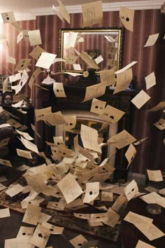 many pieces of paper are flying in the air near a mirror and table with writing on it