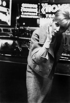 a black and white photo of a woman talking on a cell phone while standing in front of a store