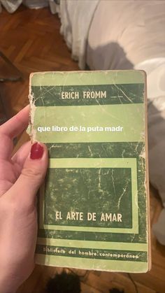 a person holding up an old book in their hand with spanish writing on the cover