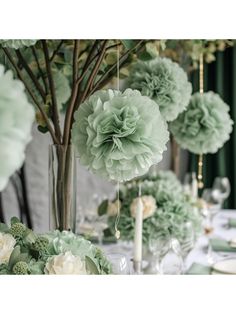 there are many green flowers in vases on the dining room table with candles and place settings