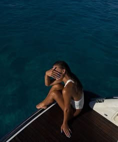 a woman sitting on the deck of a boat talking on her cell phone