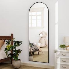 a white teddy bear sitting on a bed in front of a large mirror that is reflecting it's image