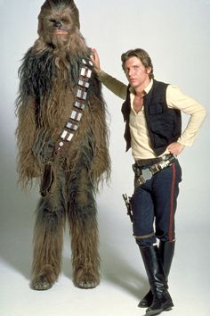 a man standing next to a woman dressed as chew - oo from star wars