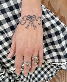 a woman's hand with a tattoo on her left wrist and two rings in the middle