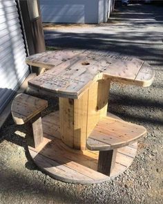 a wooden table and bench sitting on top of a gravel road next to a building