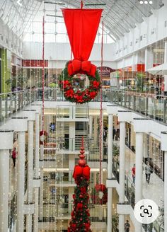 the inside of a shopping mall decorated with christmas wreaths and red bow hanging from the ceiling