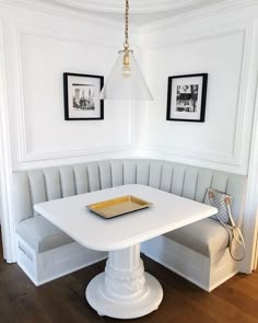 a white table and bench in a room with two pictures on the wall behind it