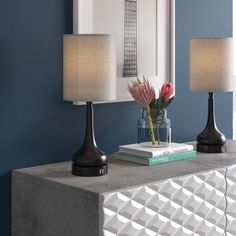 two lamps sitting on top of a table next to a vase with flowers in it