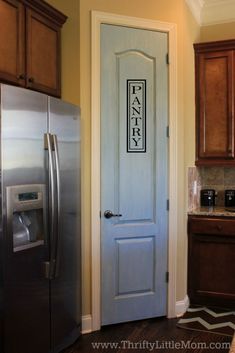 a kitchen with a blue door and stainless steel refrigerator next to wooden cabinets in it