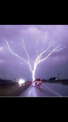 a lightning bolt is seen in the sky over a highway as cars drive down it