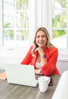 a woman sitting at a table in front of a laptop computer