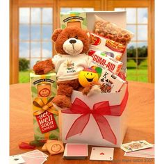 a teddy bear sitting in a gift box filled with snacks and candys on a table