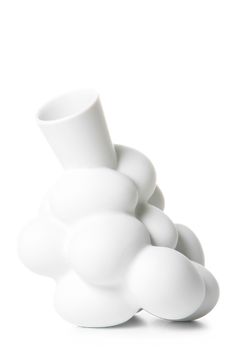 a white vase sitting in the middle of a pile of white balls on top of each other