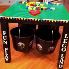 a lego table with two buckets on it and the words fun lego play painted on them