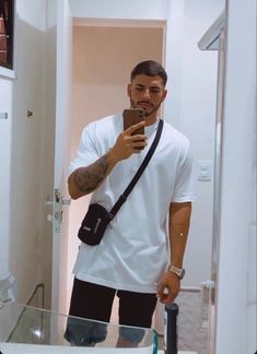 a man taking a selfie in the mirror with his cell phone and camera bag