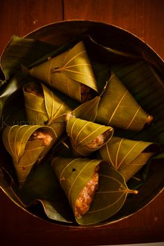 some food is sitting in a bowl on a wooden table and it looks like leaves