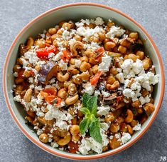 a bowl filled with lots of food sitting on top of a gray counter next to a green leaf