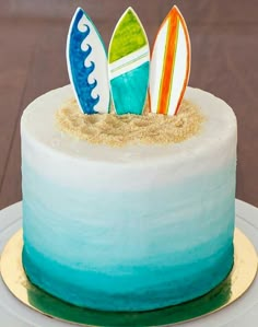 there is a cake that has three surfboards on it and sand in the middle