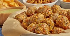 a bowl filled with meatballs next to bowls of chips