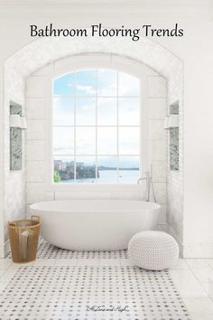 a large white bathtub sitting under a window next to a basket on the floor