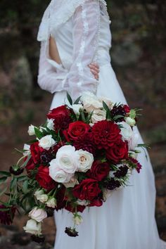 a bride holding a bouquet of red and white flowers