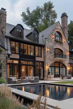 A luxurious estate featuring a grand stone exterior with large, elegant windows and a modern pool area, blending classic architectural design with contemporary luxury. Modern French Architecture, Dark Modern Farmhouse Exterior, Mansions Luxury Exterior, Coastal Ranch, Classic Mansion