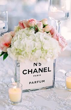 a table topped with candles and flowers on top of a white table cloth next to wine glasses