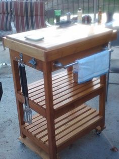 a wooden cart with utensils on it sitting in the middle of a patio