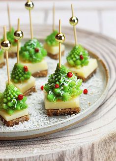 small desserts are arranged on a plate with toothpicks in the shape of trees