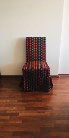 a red and black chair sitting on top of a hard wood floor next to a white wall