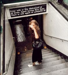 a woman walking down an escalator with her hand up to her face