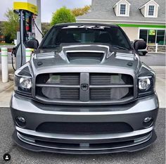 the front end of a gray dodge ram truck parked at a gas station with an electric charger in the background