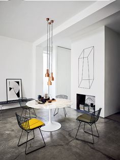 a white table and chairs in a room with art on the wall behind it, next to a fireplace