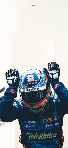 a man with his hands up in the air while wearing a racing suit and helmet