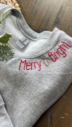 a christmas sweater with holly and mist on the front, sitting on a wooden floor