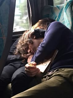 two people sleeping on a bus next to each other with their eyes closed and one person holding an apple