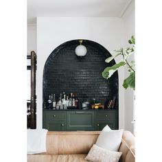 a living room filled with furniture and lots of bottles on top of a shelf next to a potted plant